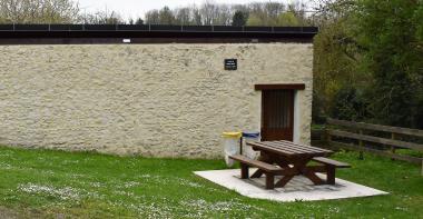 Table de bois et poubelles devant le lavoir
